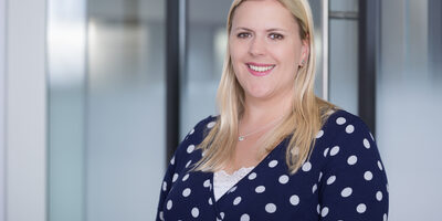 Woman in navy blue and white polka dot dress smiling at camera.